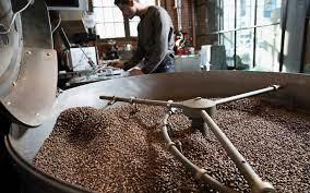 A man stands over his coffee roaster (Source: Perfect Daily Grind)